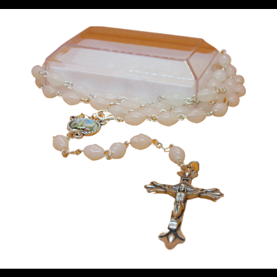 Rosário branco com crucifixo metálico sobre caixa rosa claro