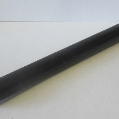 Vela preta cilíndrica com pavio branco sobre superfície branca