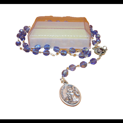 Rosário azul com contas facetadas brilhantes sobre caixa retangular branca e alaranjada