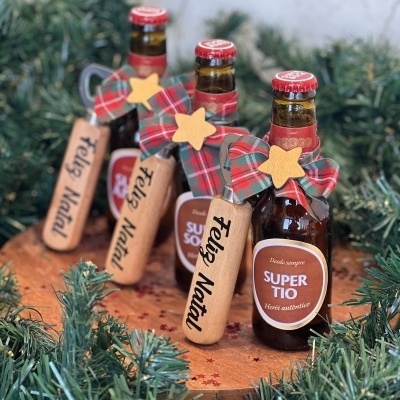 Quatro garrafas de cerveja Super Tio decoradas para Natal com etiquetas e laços em madeira e tecido xadrez