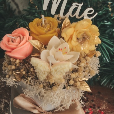 Arranjo decorativo com flores artificiais coloridas, folhas douradas, musgo seco e texto em madeira 'Mãe'
