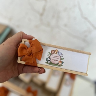 Caixa de madeira com laço alaranjado e etiqueta personalizada para batizado
