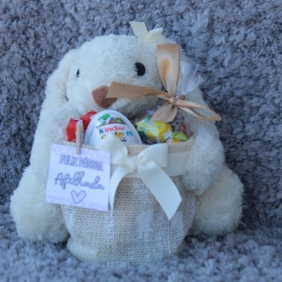 Pelúcia de ovelha segurando saco de juta com brinquedos e ovo Kinder