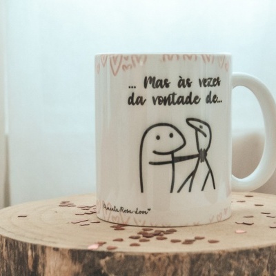 Caneca branca com figura e texto em preto sobre tronco de madeira