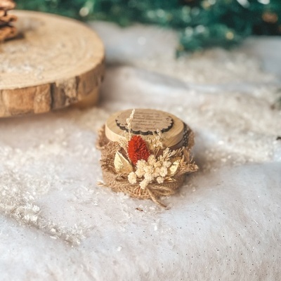 Frasco decorado com flores secas e tampa de madeira sobre superfície branca
