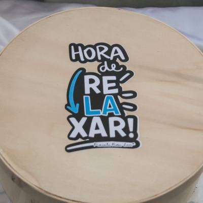 Caixa redonda em madeira clara com texto Hora de Relaxar