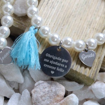 Pulseiras com pendentes metálicos e tassel azul sobre pedras e madeira