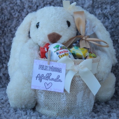 Coelho de pelúcia branco com saco de tecido contendo chocolates Kinder e cartão de Páscoa