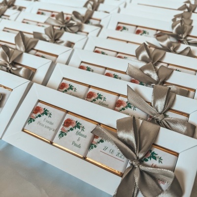 Caixas brancas com chocolates decorados e laços cinzentos