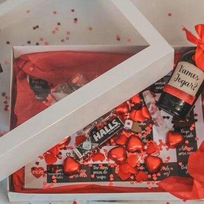 Caixa de presente com garrafa, chocolates e corações vermelhos