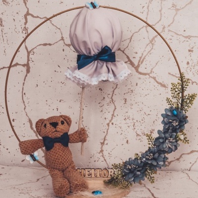 Decoração circular com urso de tricô, balão de tecido e flores azuis