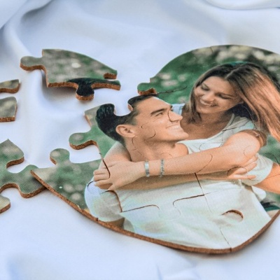 Quebra-cabeça de madeira em forma de coração com imagem de casal sobre tecido branco