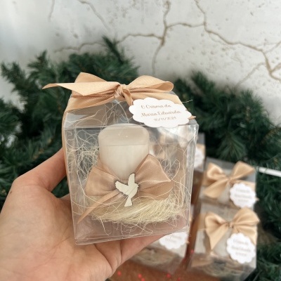 Castiçal branco com laço castanho claro numa embalagem transparente.