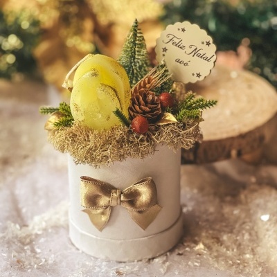 Arranjo natalício com vela amarela e decoração em caixa branca com laço dourado