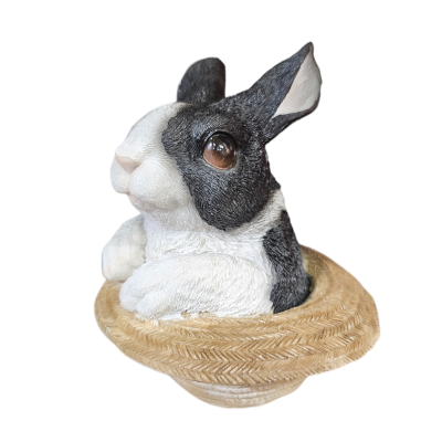 Escultura de coelho preto e branco numa base que parece chapéu de palha
