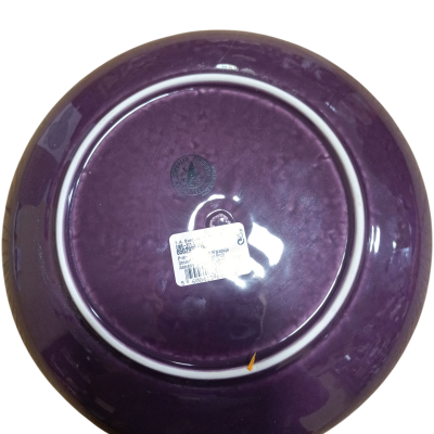 Prato de cerâmica roxo visto pela parte de trás com etiqueta e marca no centro.