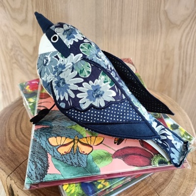 Pássaro de tecido floral sobre caixas coloridas em madeira