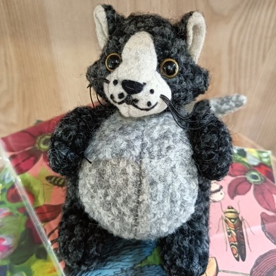 Boneco de peluche de lobo cinzento e branco sobre livro colorido com padrão floral