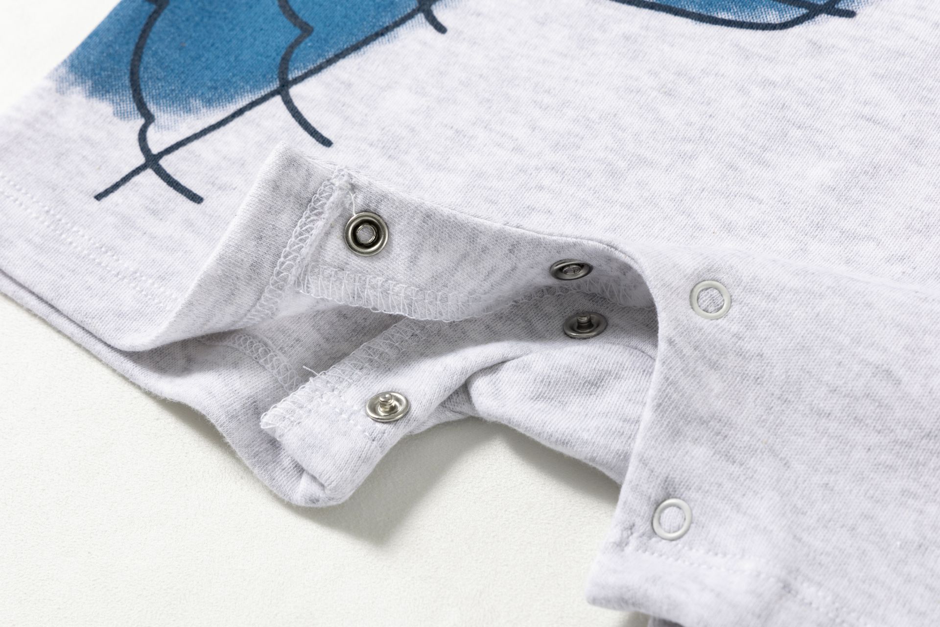 Peça de roupa cinzenta com botões de pressão e padrão em azul e preto