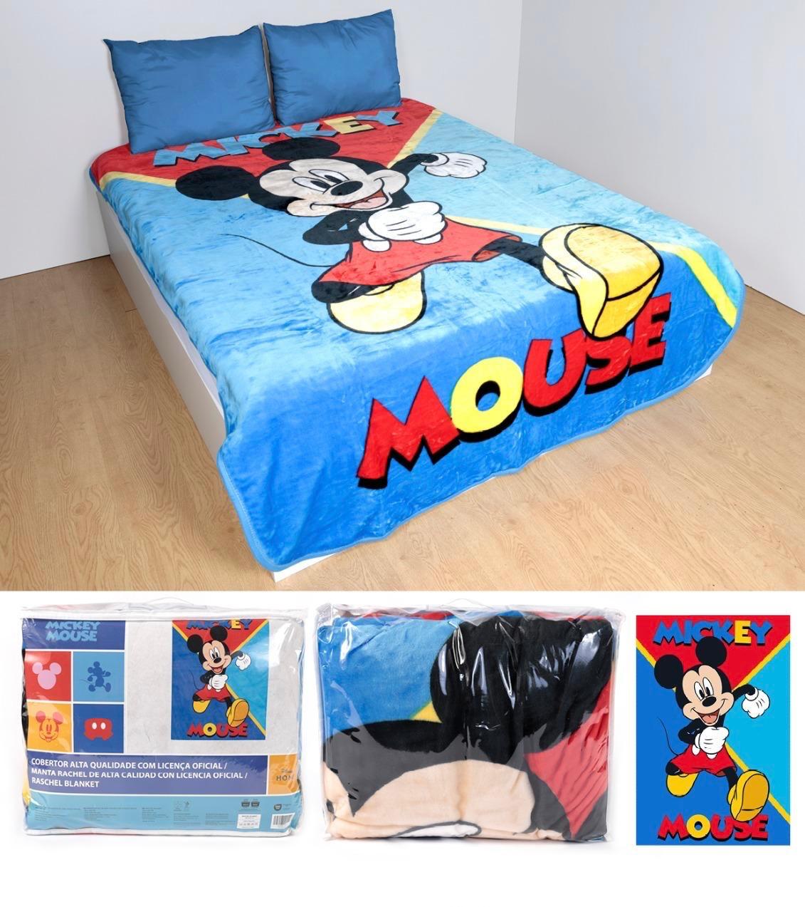 Cobertor azul com imagem do Mickey Mouse e texto MICKEY MOUSE numa cama com duas almofadas azuis