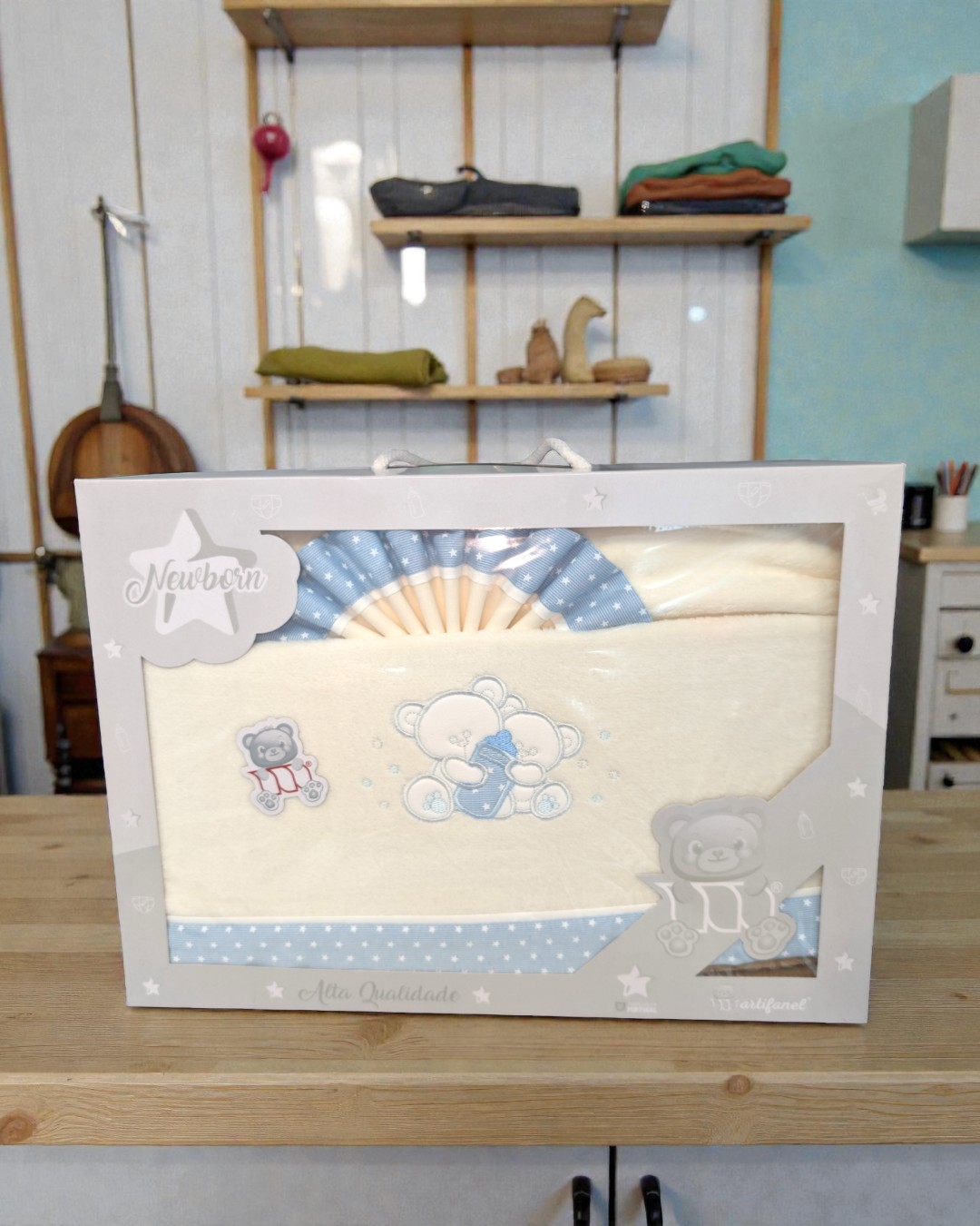 Conjunto de roupa de bebé em embalagem branca com detalhes de ursinhos e padrão azul com estrelas.