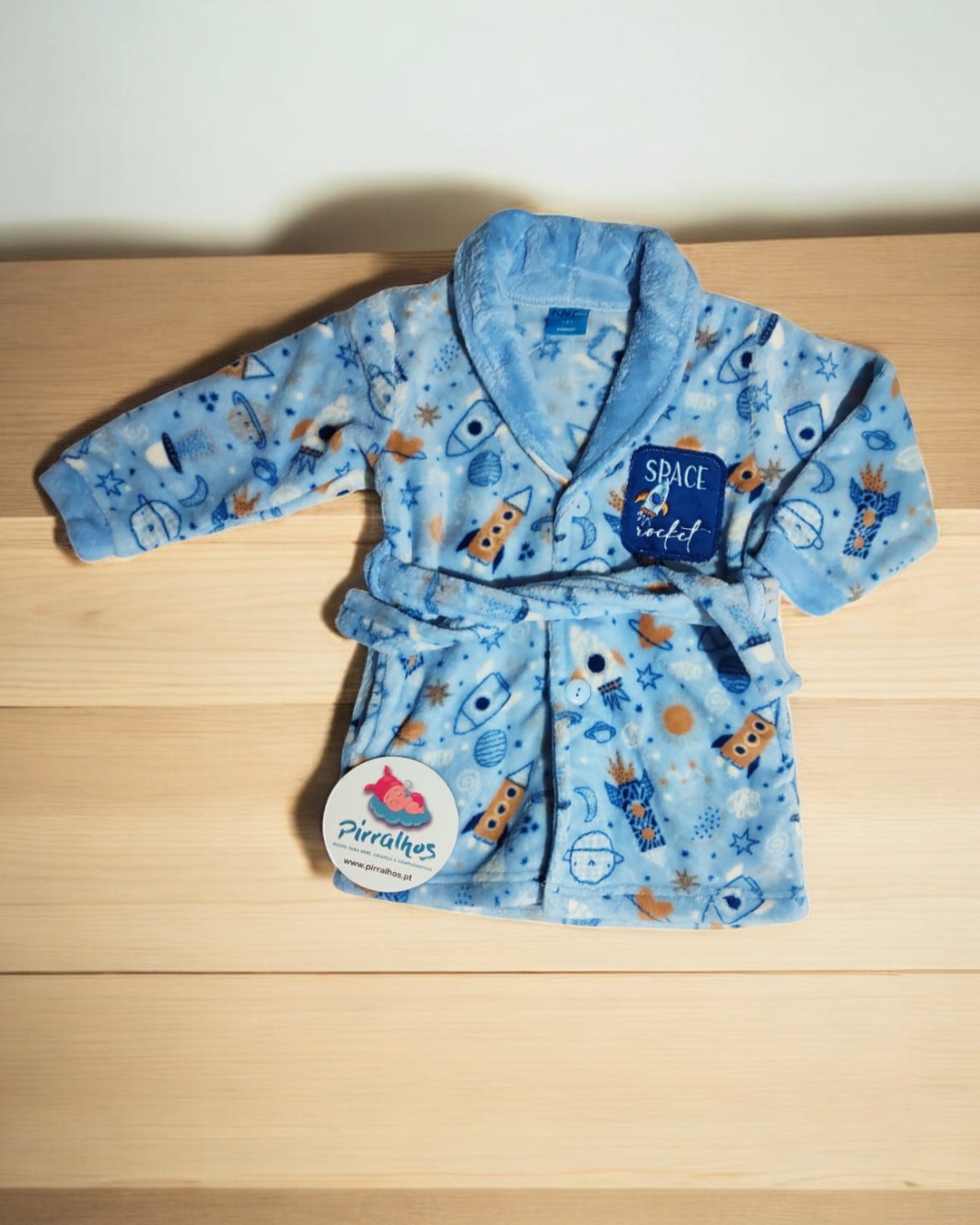 Roupão infantil azul com padrão espacial e etiquetas visíveis