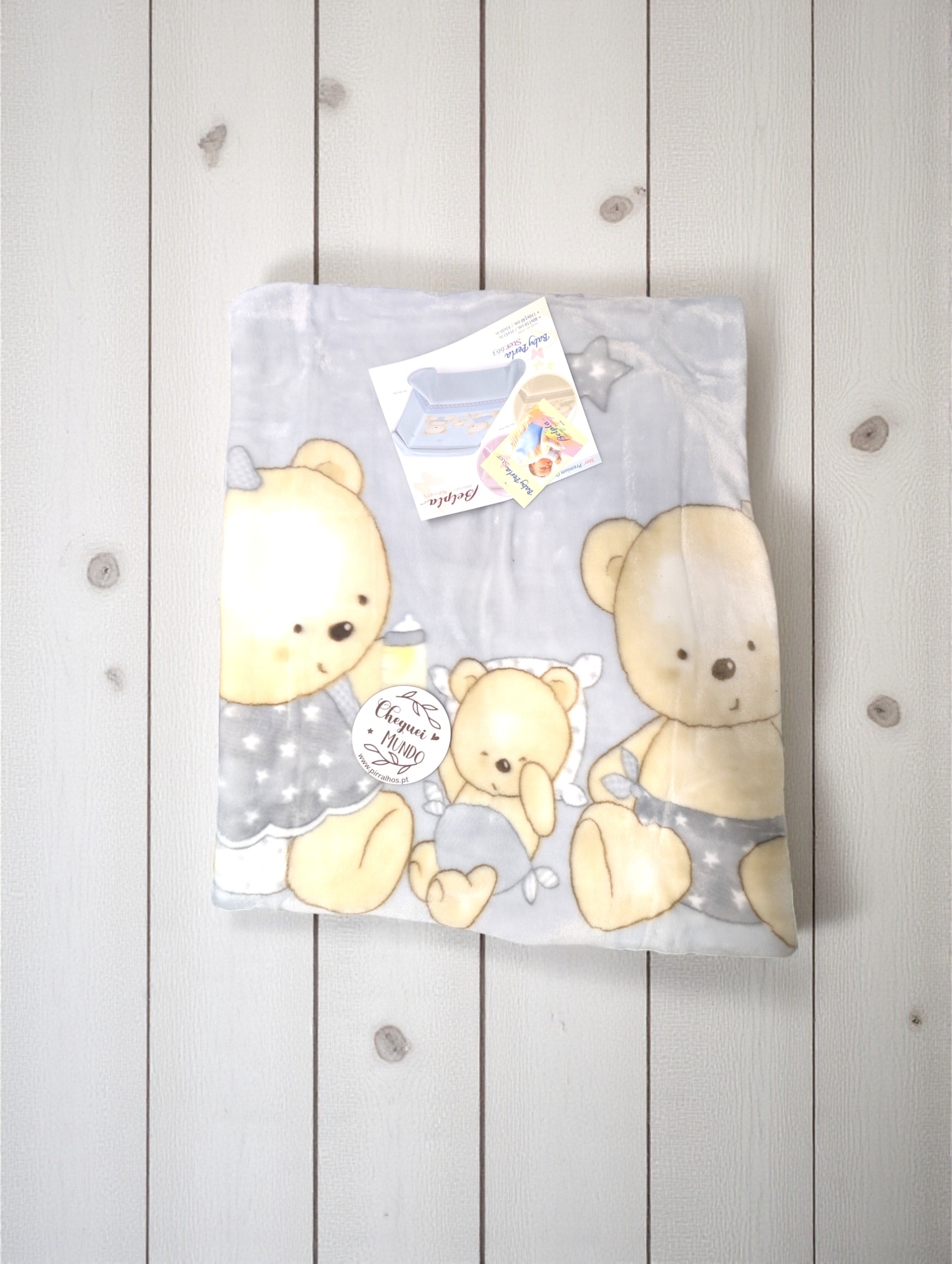 Cobertor cinza com desenho de ursos e etiqueta redonda com texto