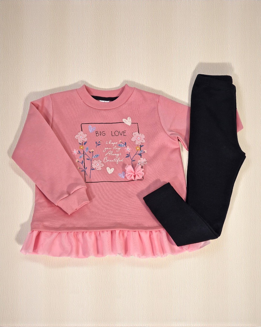 Conjunto de roupa infantil rosa e preta com padrão floral e texto em sweat rosa