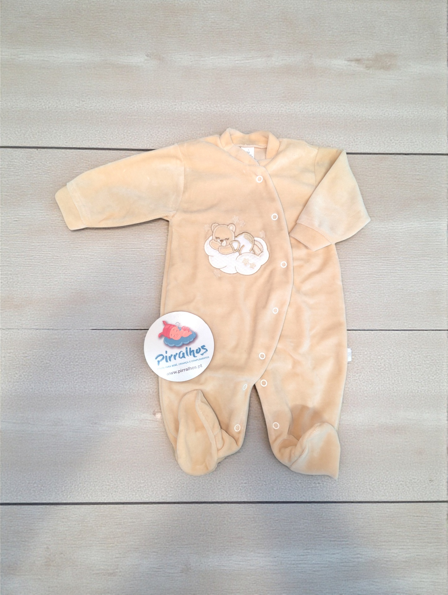 Pijama felpudo bege para bebé com ursinho bordado e etiqueta da marca Pirralhos