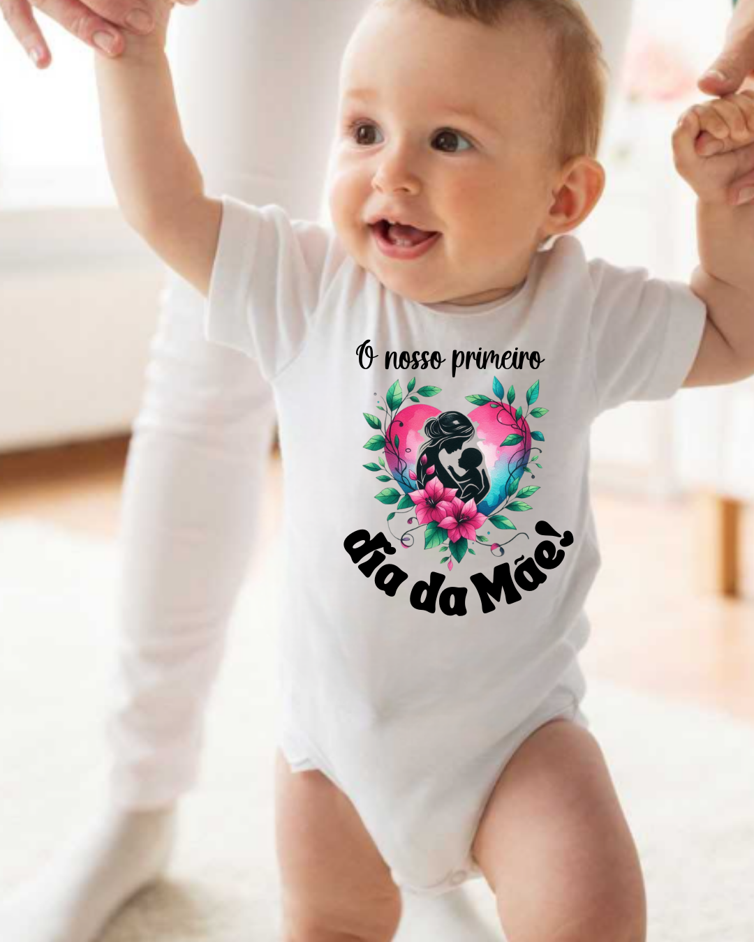 Bebé com body branco estampado 'O nosso primeiro dia da Mãe!' em ambiente interior