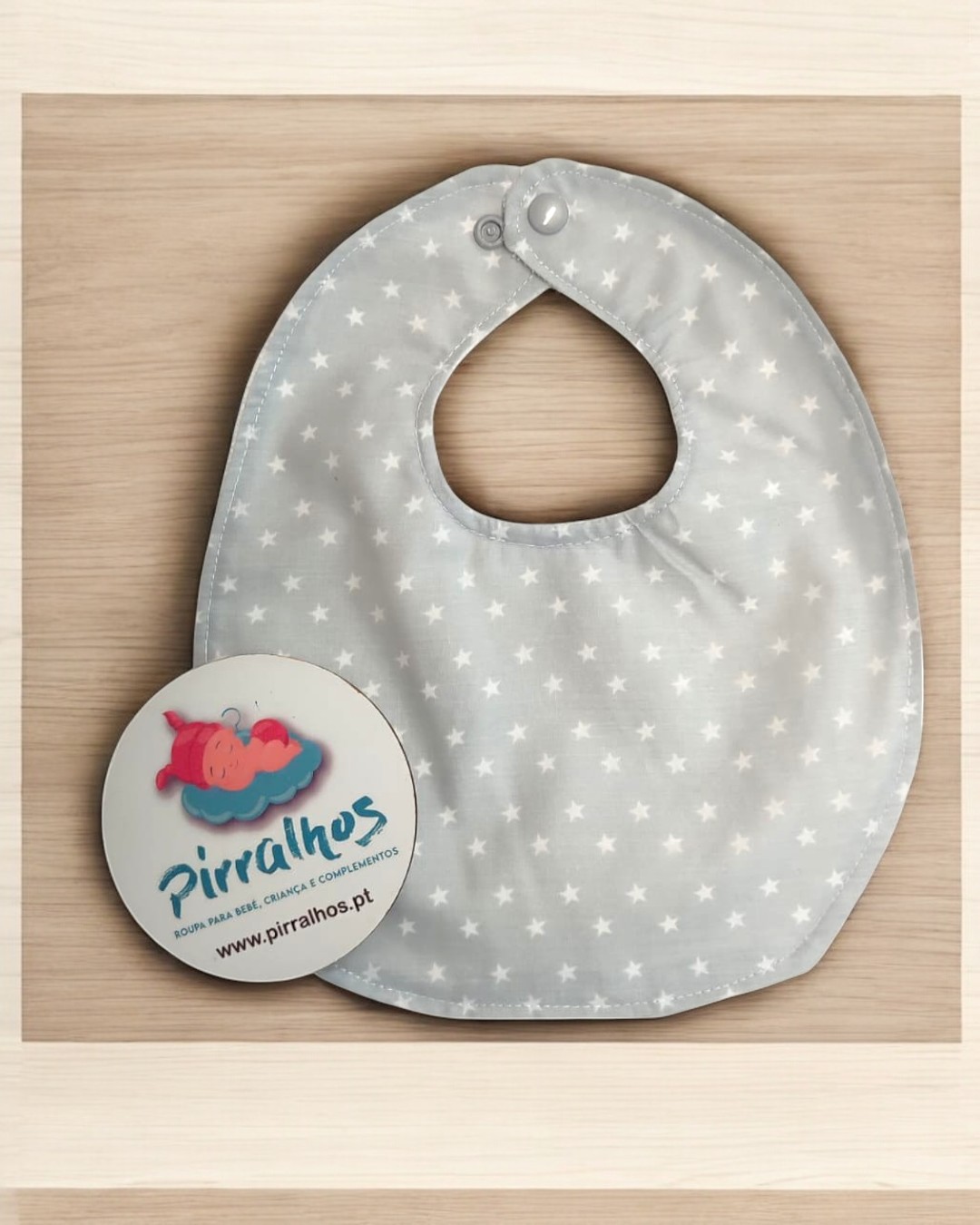 Babete cinza com estrelas brancas e etiqueta da marca Pirralhos