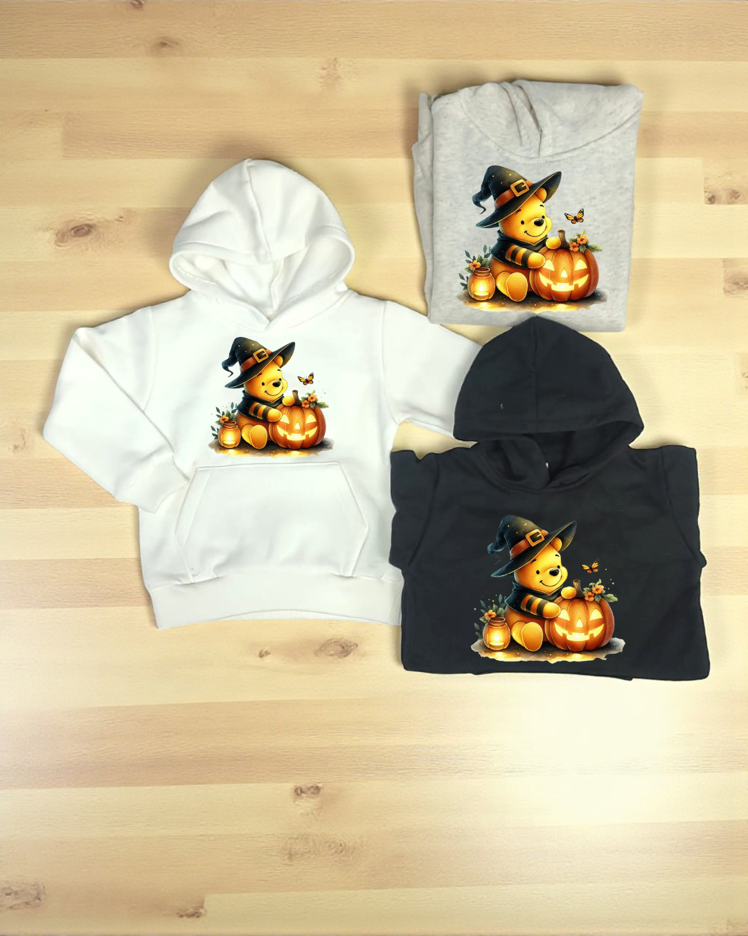 Três sweatshirts com capuz em branco, cinza e preto com estampa de urso bruxo e abóbora iluminada