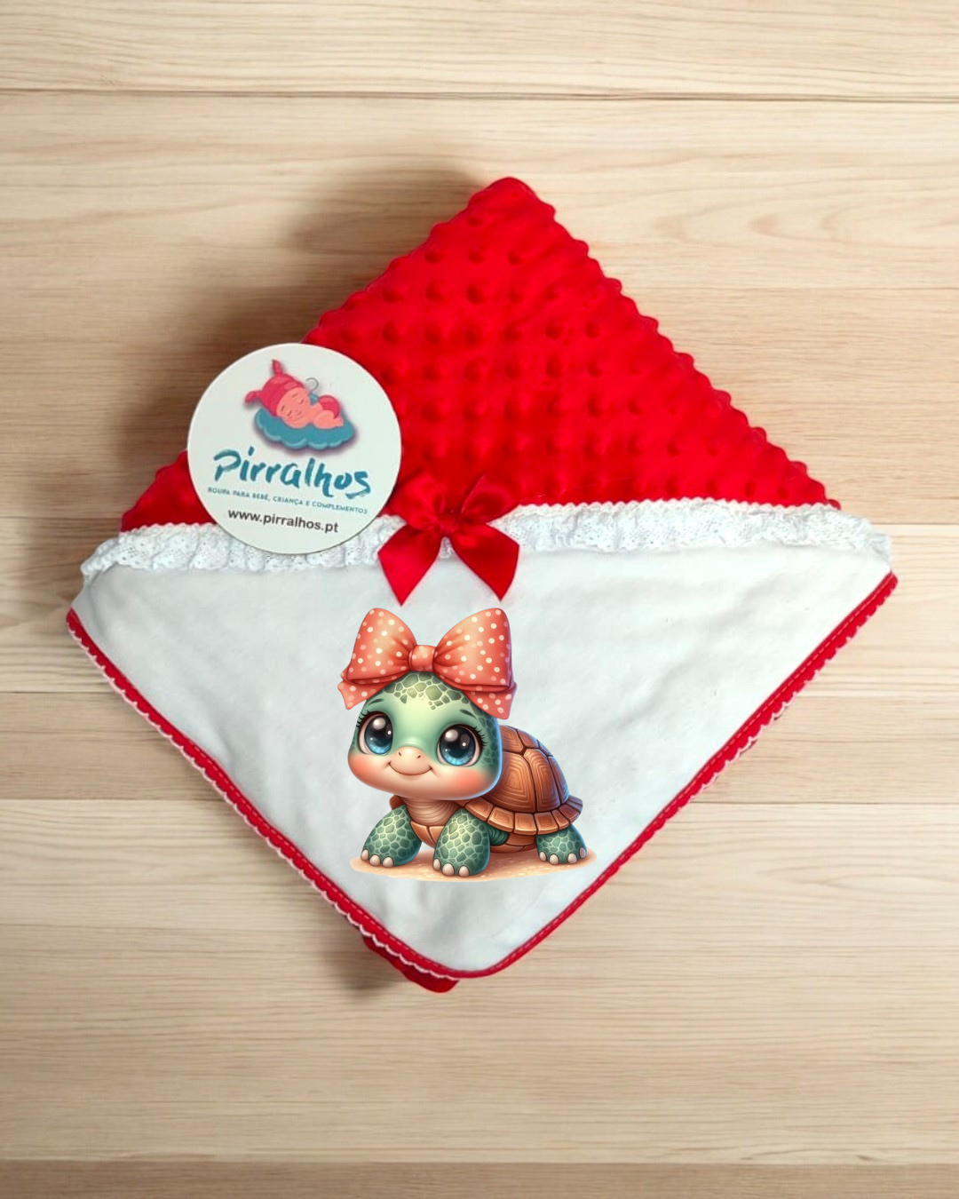 Manta de bebé vermelha e branca com desenho de tartaruga e etiqueta Pirralhos