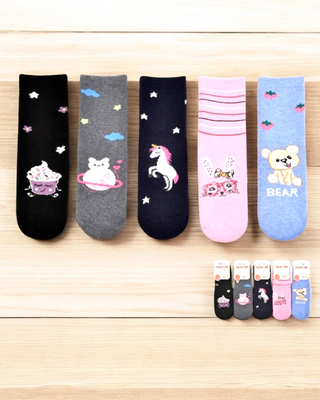 Cinco pares de meias coloridas infantis com desenhos variados e fundo de madeira clara