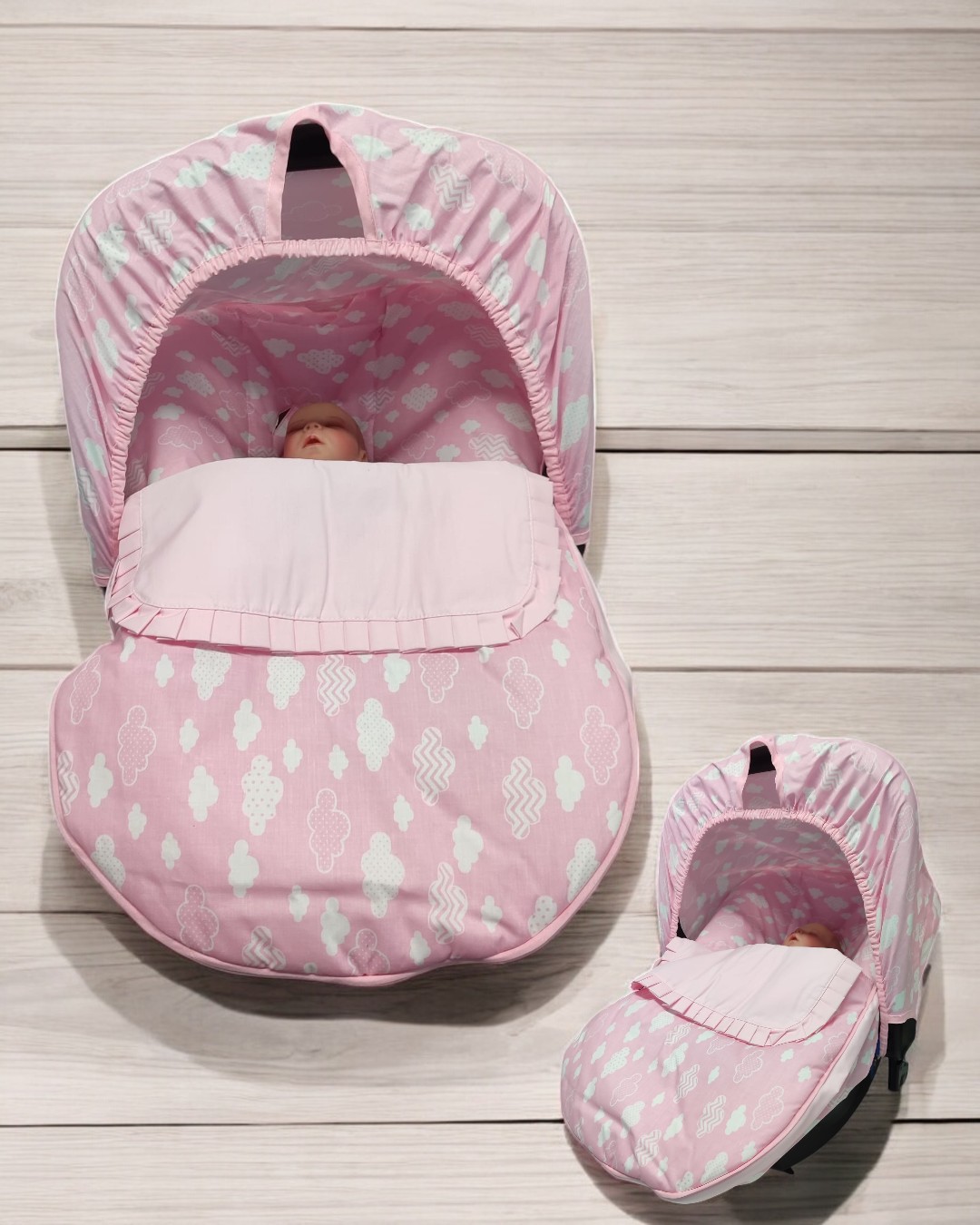 Carrinho de bebé rosa com padrão branco de nuvens e capota em fundo de madeira clara