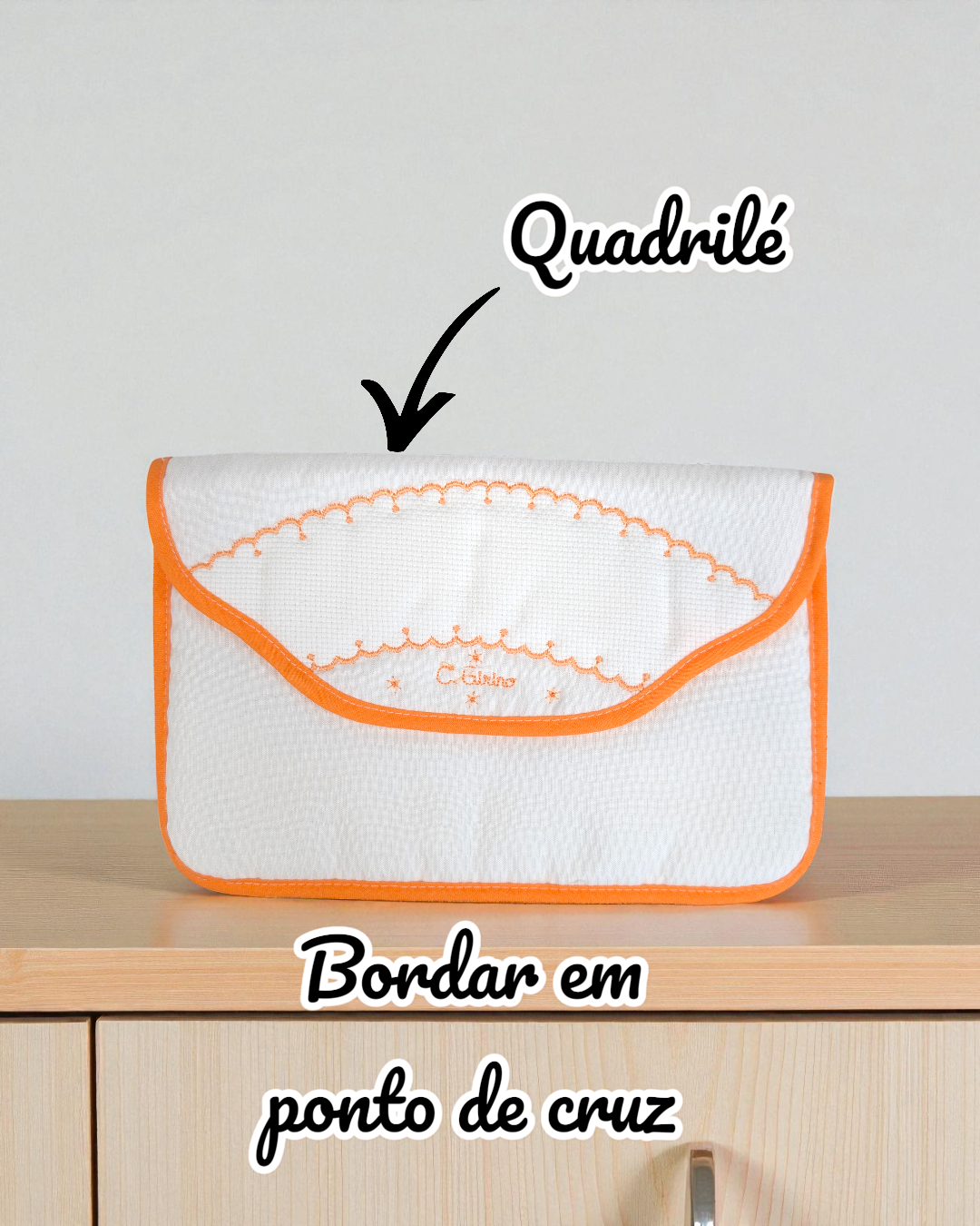 Bolsa branca com bordado laranja e borda laranja, sobre móvel de madeira clara