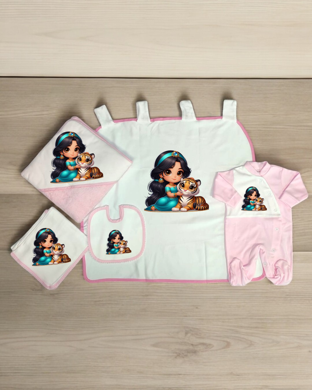 Conjunto de bebé rosa e branco com desenho de princesa e tigre sobre mesa de madeira clara