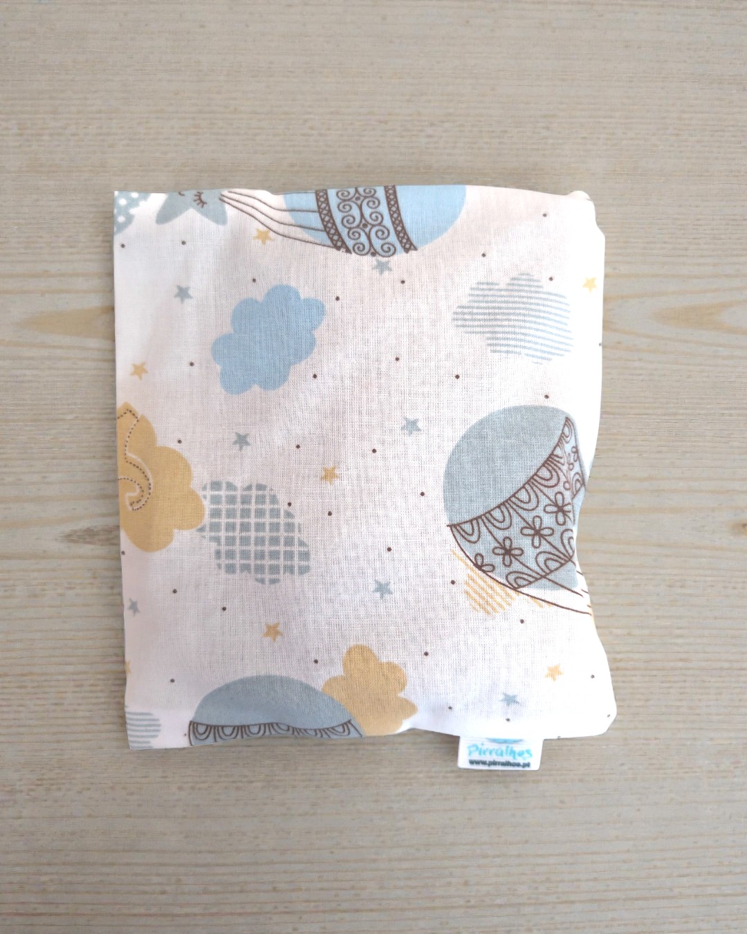 Almofada quadrada com padrão de balões e nuvens em azul, amarelo e cinzento