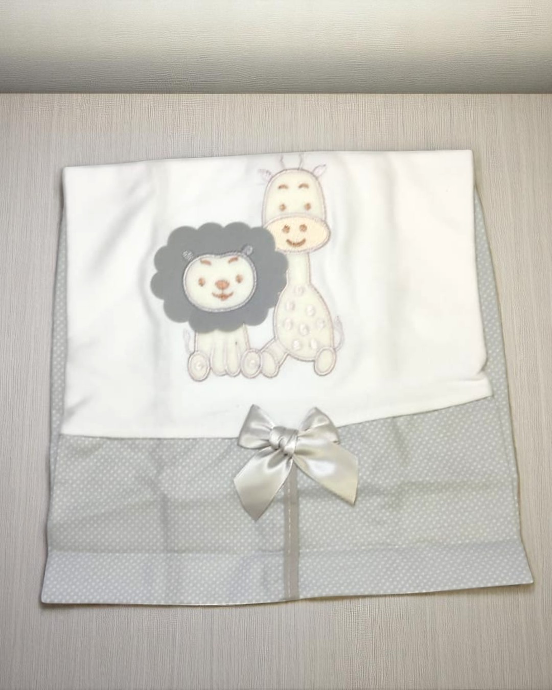 Fralda branca e cinza com bordado de leão e girafa e laço prateado