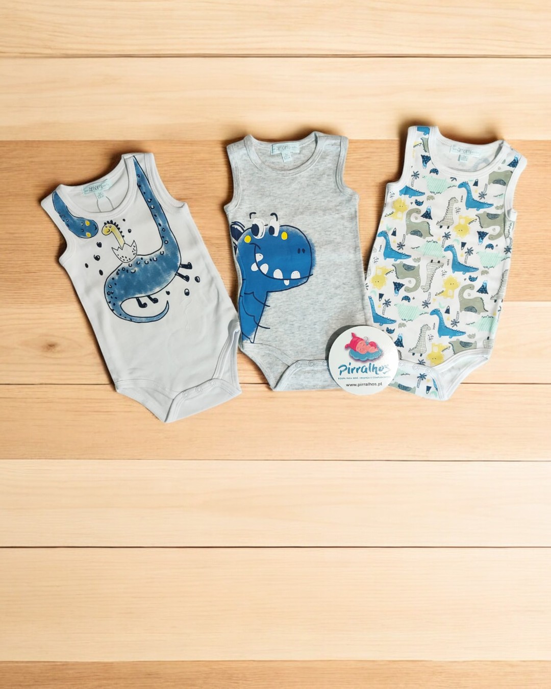 Três bodies de bebé com desenhos de dinossauros em madeira clara