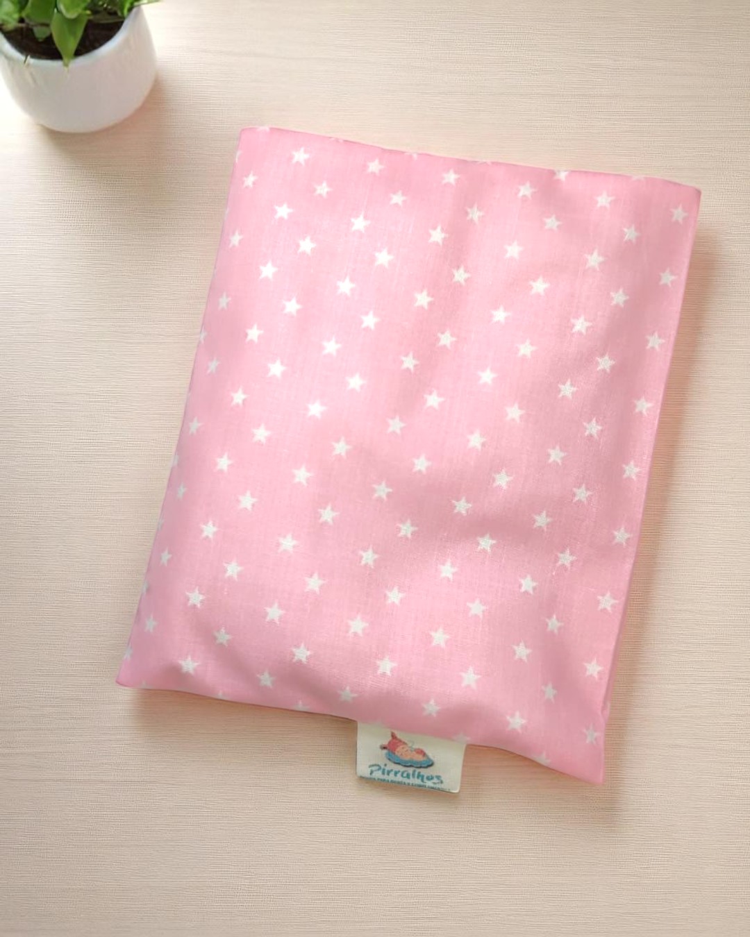 Bolsa térmica rosa com estrelas brancas sobre mesa clara e planta