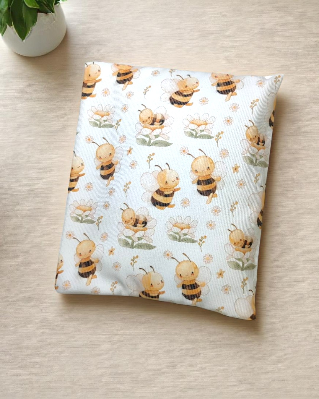 Capa de almofada com padrão de abelhas e flores sobre mesa clara