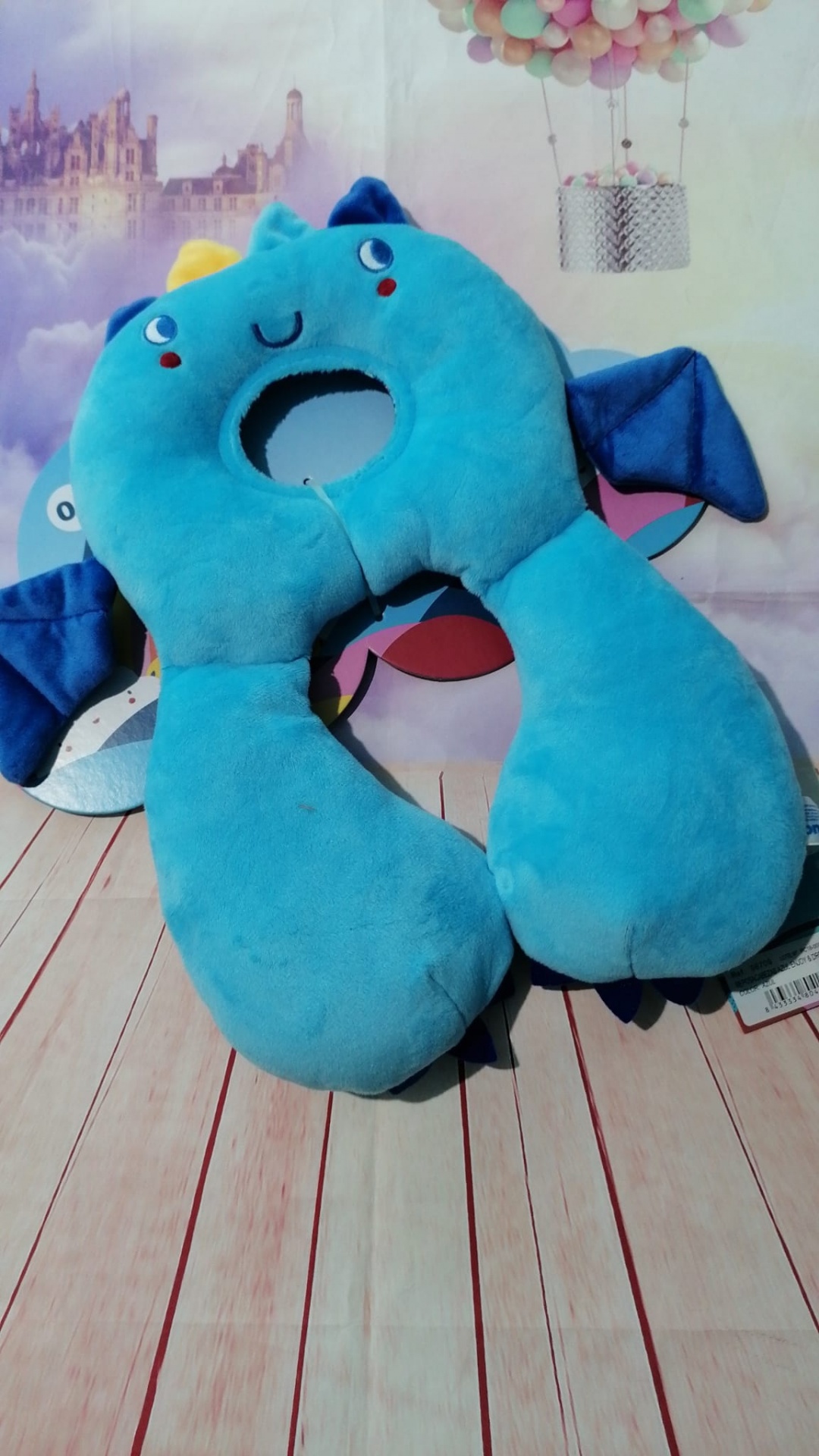 almofada de viagem azul em forma de personagem com olhos e sorriso