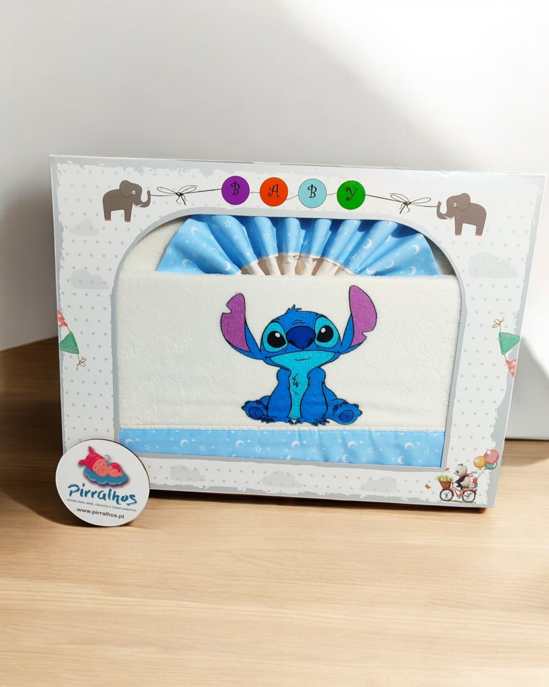 Fralda branca com faixa azul e personagem azul embalada numa caixa decorativa