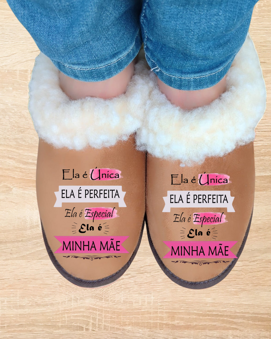Chinelos castanhos felpudos com texto para mãe, usados por pessoa com calças de ganga azuis
