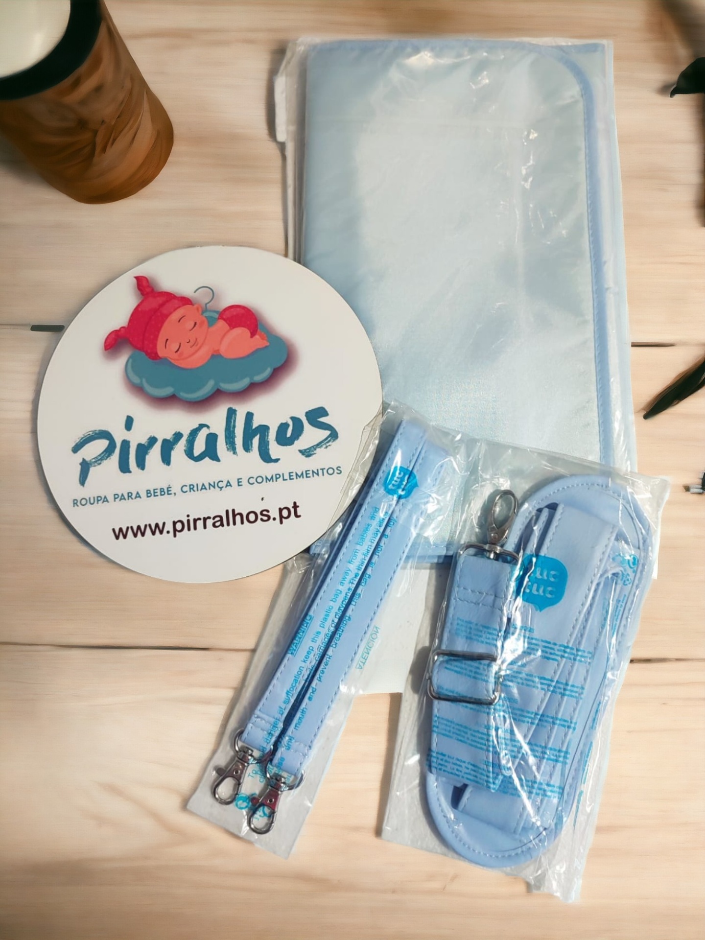 Produtos infantis azuis com embalagem plástica e placa promocional Pirralhos em fundo de madeira