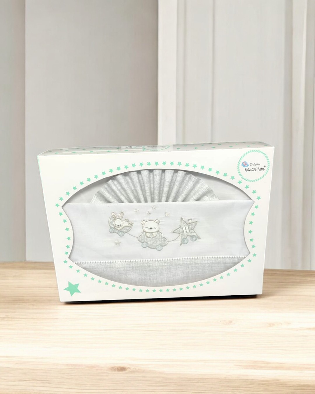 Conjunto de roupa de bebé cinza claro com babete branco bordado dentro de caixa branca com estrelas verdes