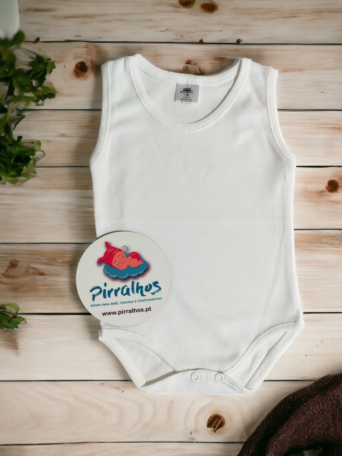 Body branco simples para bebé com fecho molas, sobre madeira clara e plantas verdes