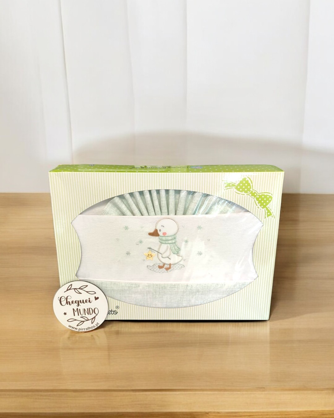 Babete branco com bordado de pato, dentro de caixa decorada com borboleta verde e etiqueta CHEGUEI AO MUNDO