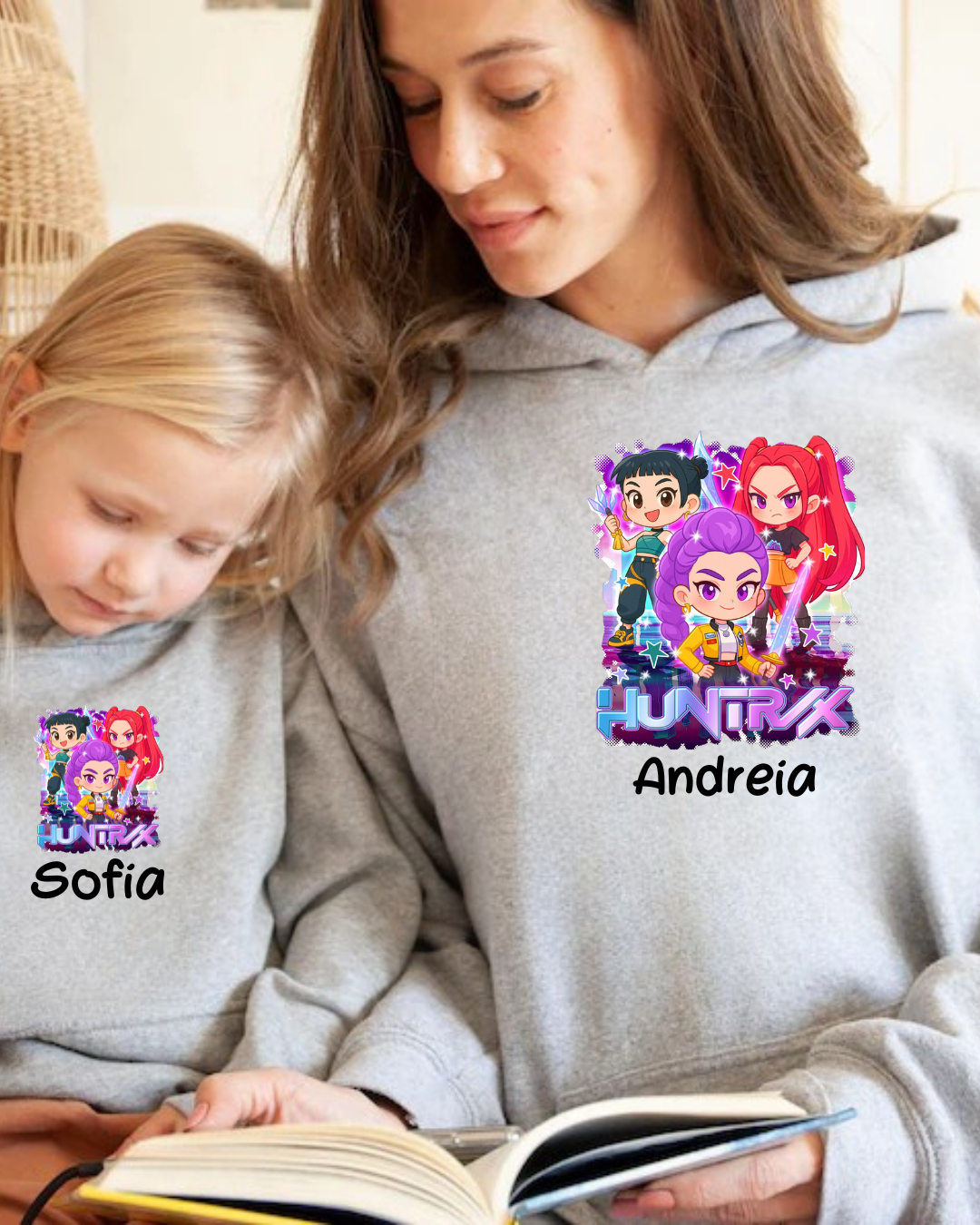 Duas pessoas com casacos de capuz cinzentos, cada um com estampa colorida e nomes 